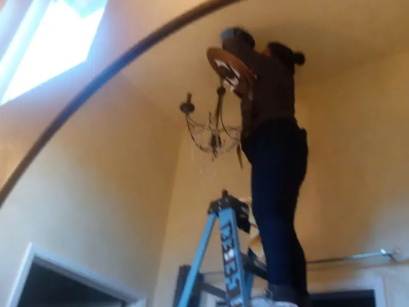 Electrician installing a chandelier in a Schroeppel residence
